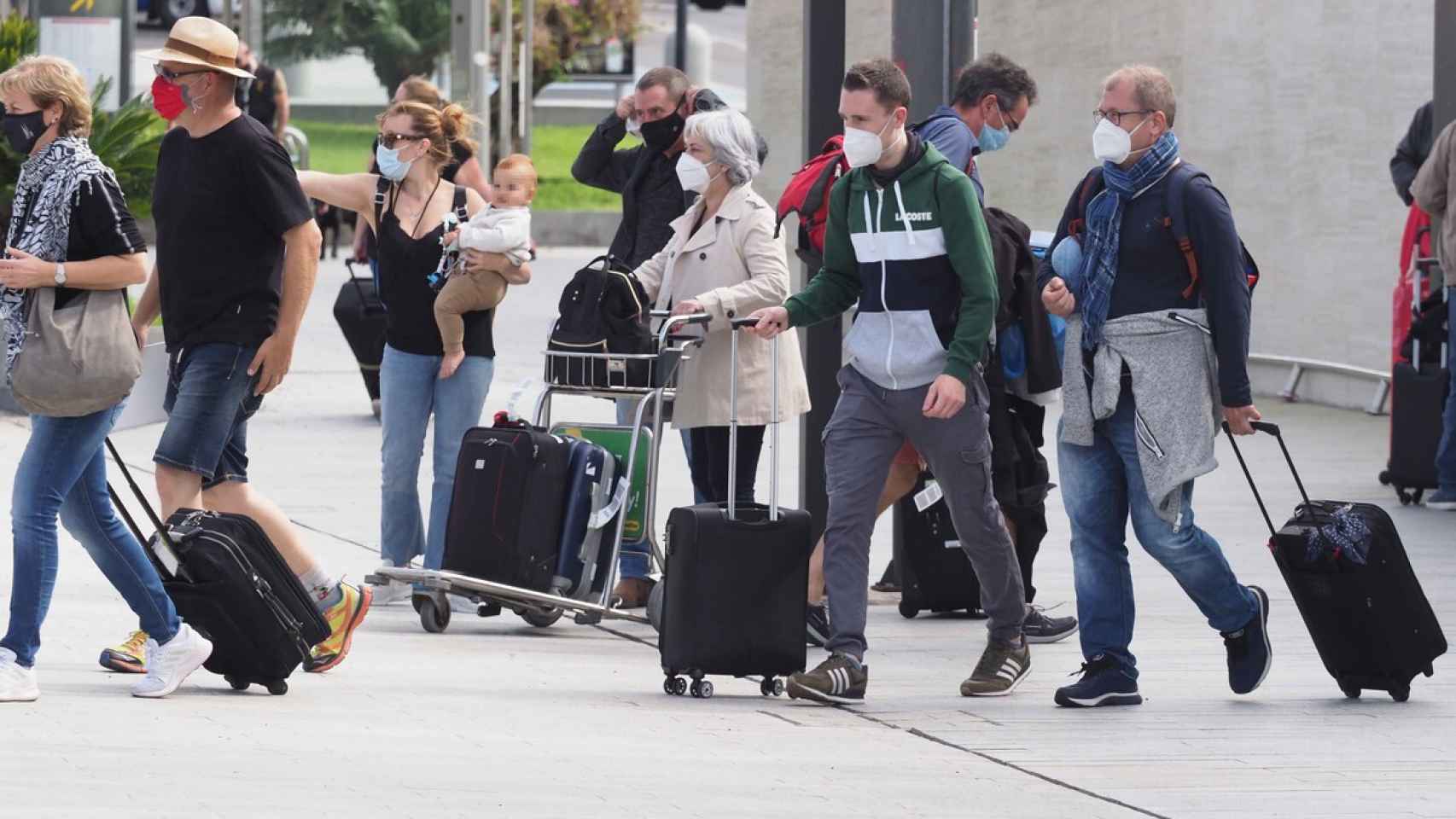 Personas con mascarilla saliendo de un aeropuerto.