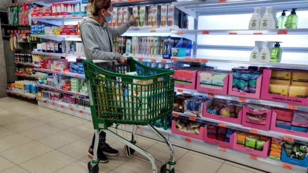 Una consumidora, en un supermercado, eligiendo un producto para su cesta de la compra.