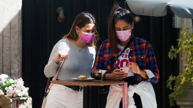 Dos jóvenes utilizando mascarillas en un bar.