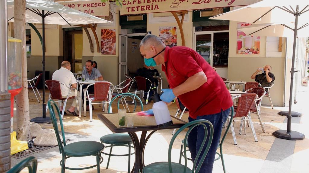 Un camarero prepara las mesas de una terraza.