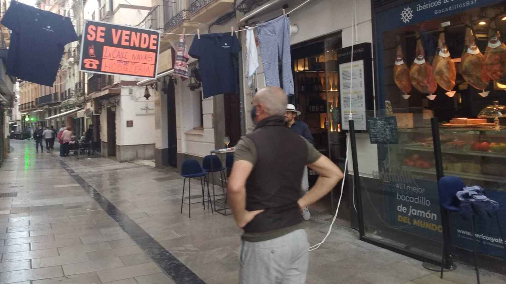 Nicolás Chica, propietario del bar Ibéricos y Alhambra, comprobando que está bien puesto el cartel de 'se vende la calle Navas de Granada'.
