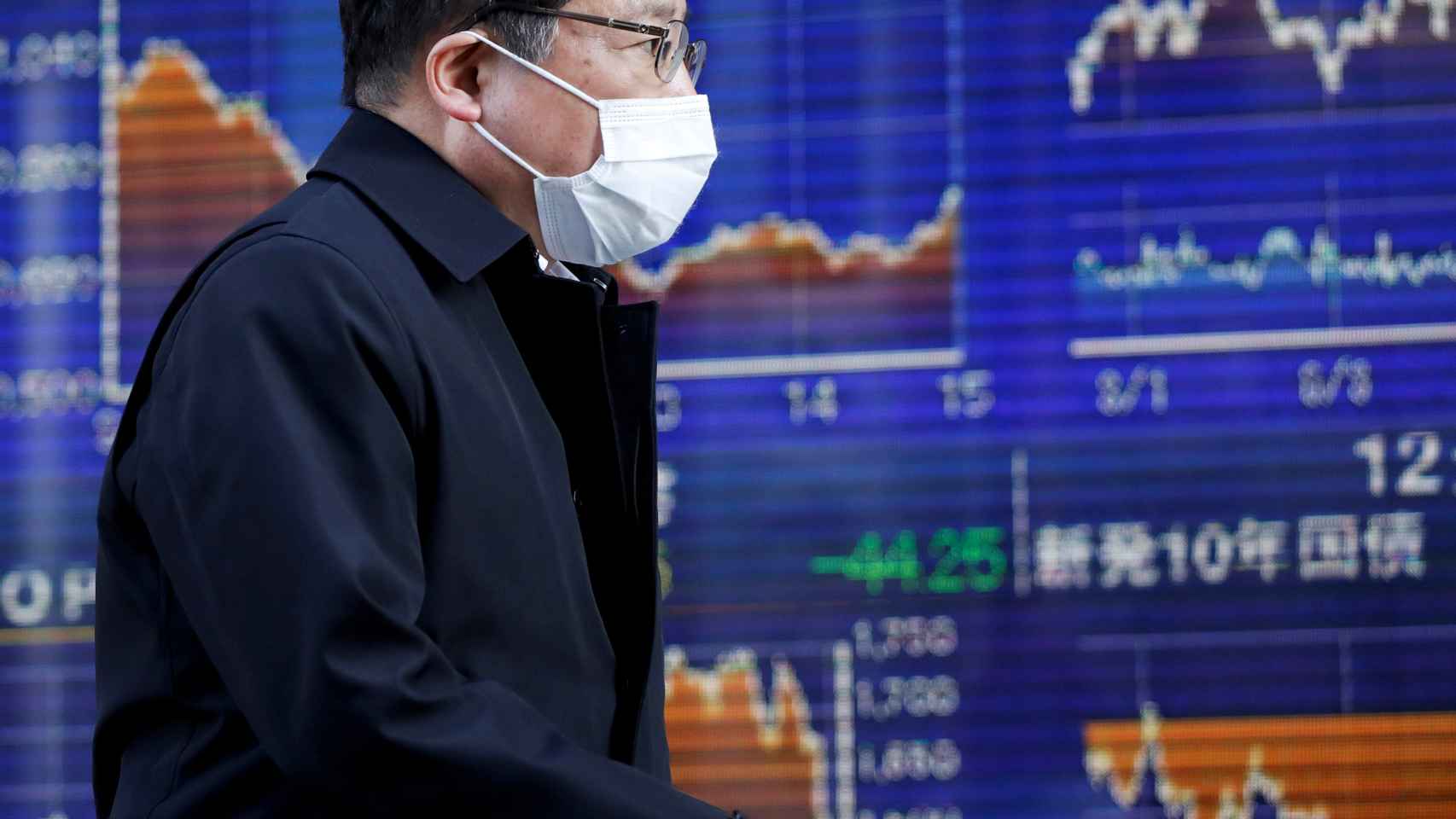 Un bróker pasa por delante de unas pantallas de negociación en la Bolsa de Tokio.