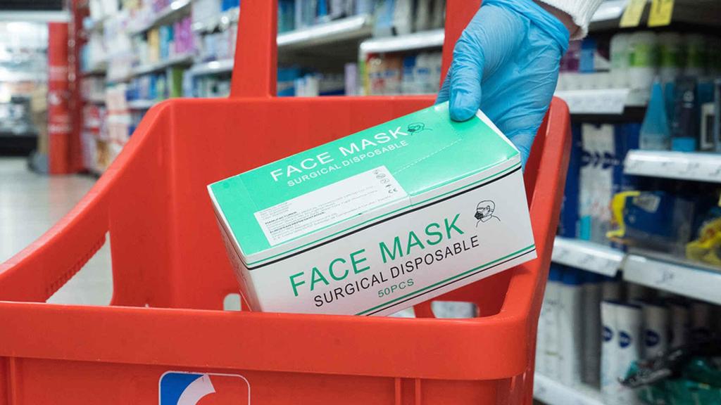 Una persona adquiere un paquete de mascarillas en un supermercado Eroski.