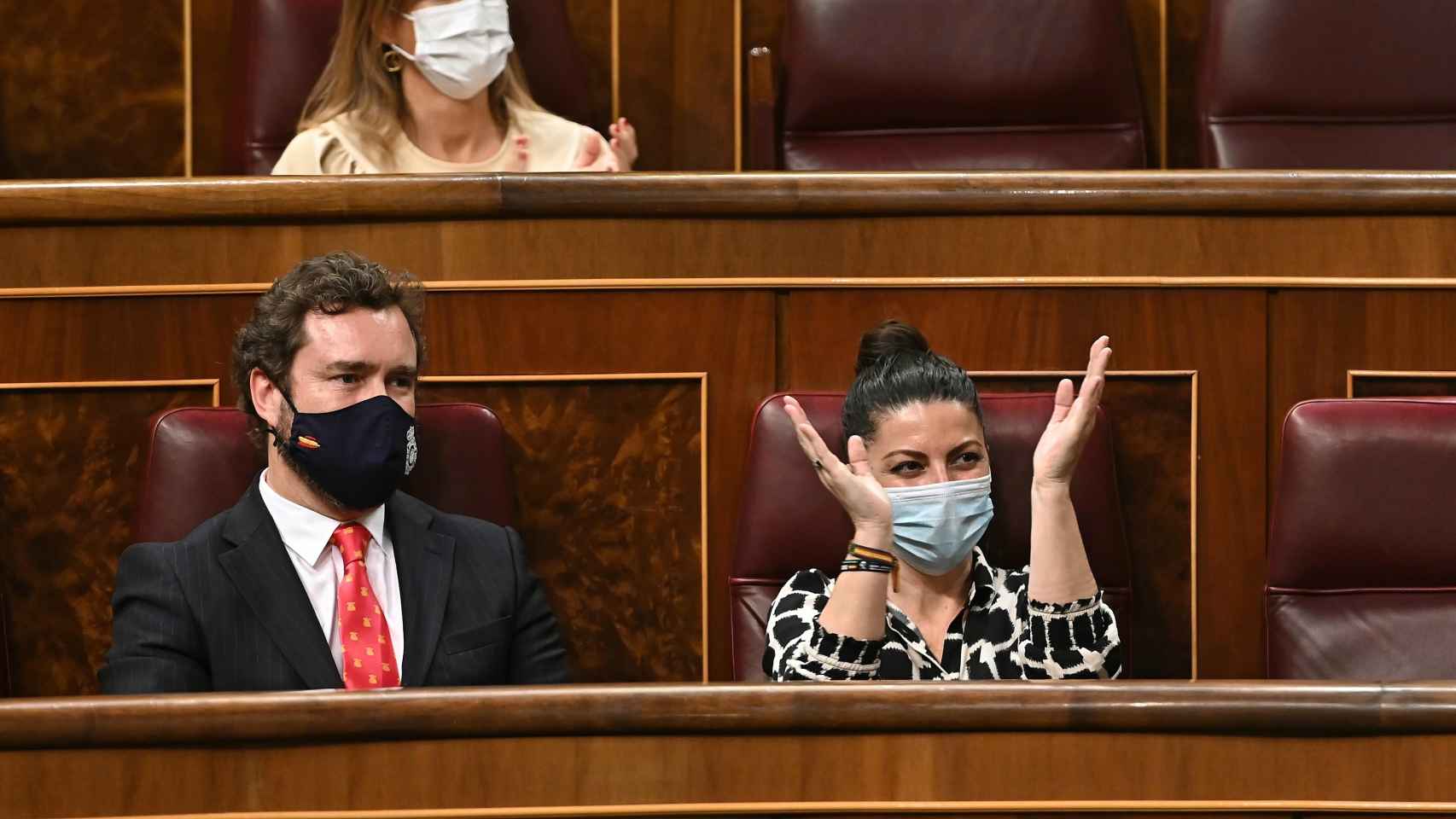 a diputada de Vox Macarena Olona aplaude en presencia del portavoz parlamentario de su formación, Iván Espinosa de los Monteros.