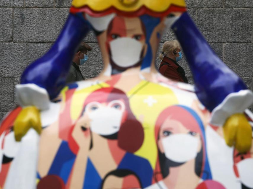 Dos personas pasean tras la figura de una menina inspirada en la Covid en Madrid.