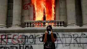 Un hombre protesta frente del Congreso de Guatemala, en llamas.