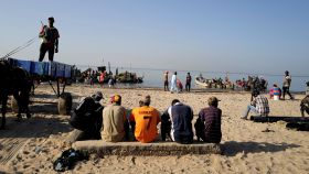 Un grupo de hombres observa a los pescadores en una playa de Joal-Fadiouth.