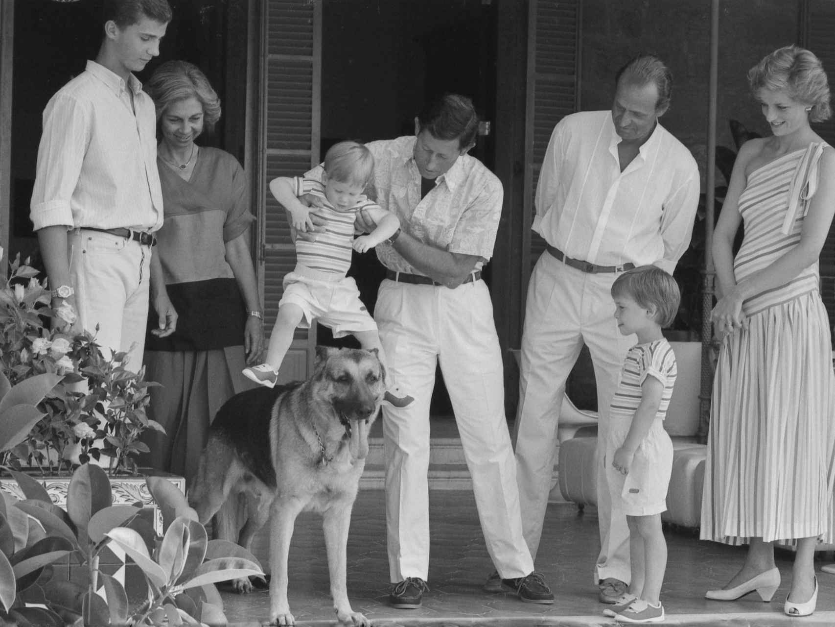 El príncipe de Gales toma en brazos a su hijo Harry y lo pone encima de Arky, el perro del rey Juan Carlos.