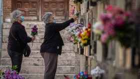 Varias mujeres colocan flores en una tumba del cementerio de Alcalá.