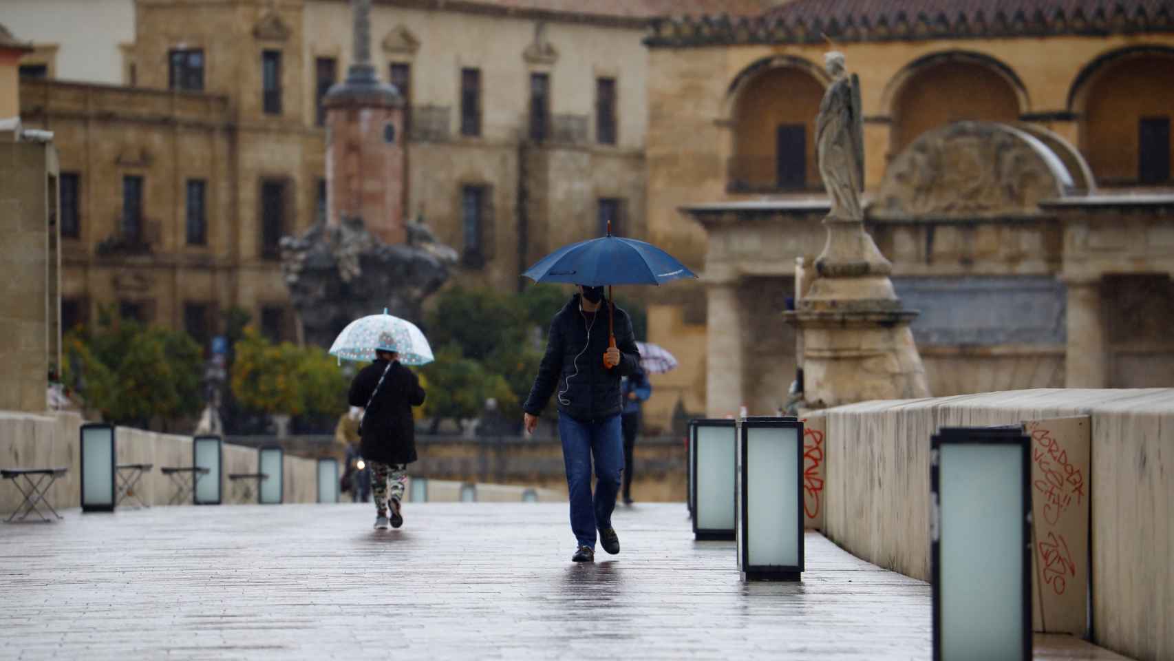 Unas personas mientras caminan este jueves por el Puente Romano de Córdoba.