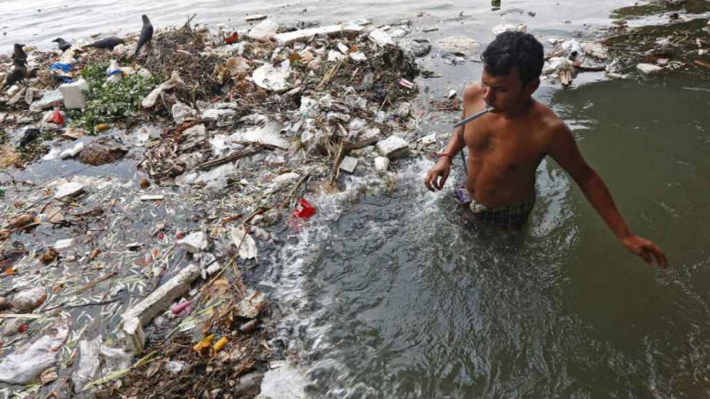 Un joven se cepilla los dientes en el agua contaminada del río Ganges en Calcuta, India.