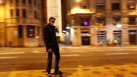 Un joven paseando en patín por Barcelona con mascarilla.
