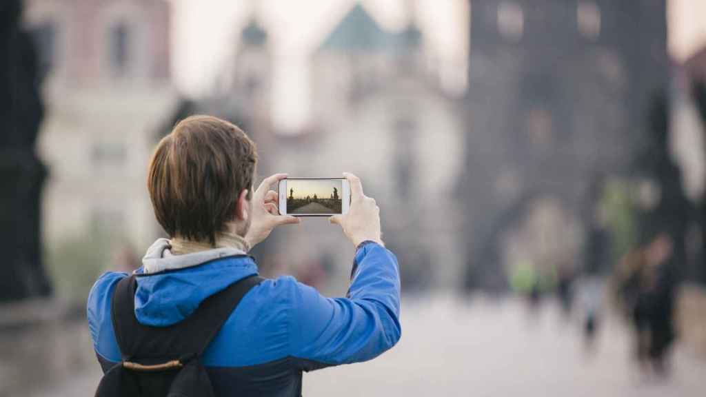Una turista fotografía el Puente de Carlos en Praga con su smartphone.