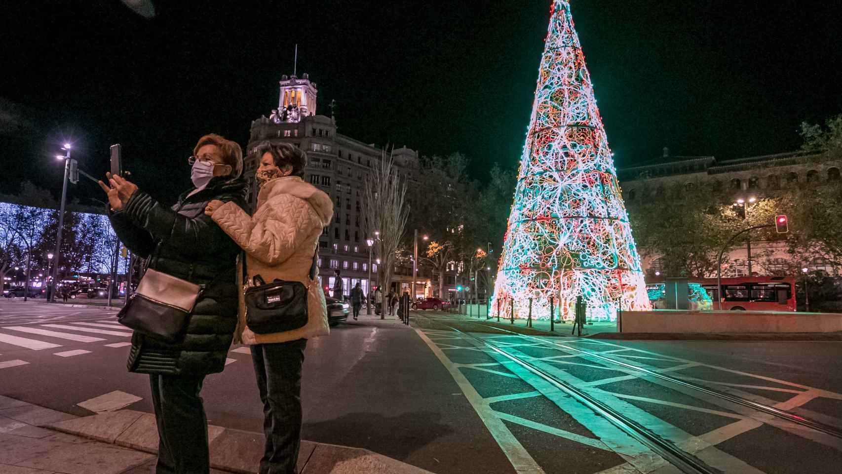 Unas mujeres se fotografían con el árbol de Navidad luminoso que se ha instalado en la Plaza de Paraíso de Zaragoza.