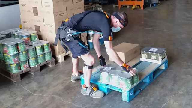 Un operario, con un exoesqueleto, carga peso en un almacén logístico.