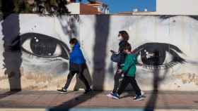Vecinos de Los Alcázares, (Murcia), pasan junto a un grafiti este miércoles.