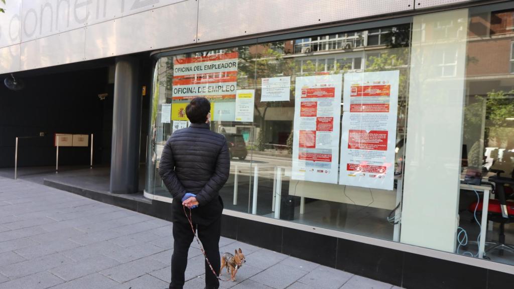 Un hombre pasa con su perro frente a una oficina de Empleo en Madrid.