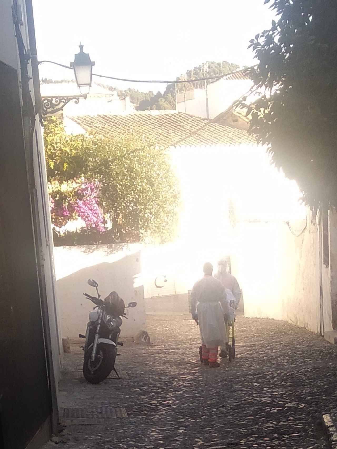 Dos sanitarios trasladando en camilla a una paciente de coronavirus por las calles del Barrio del Albaicín en Granada.