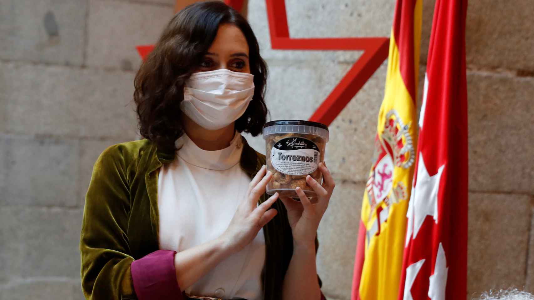 La presidenta de la Comunidad de Madrid, sujetando un bote de torreznos de La Madrileña.