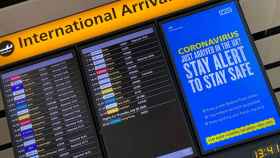 Campaña informativa del coronavirus en un panel de llegadas del aeropuerto de Heathrow.
