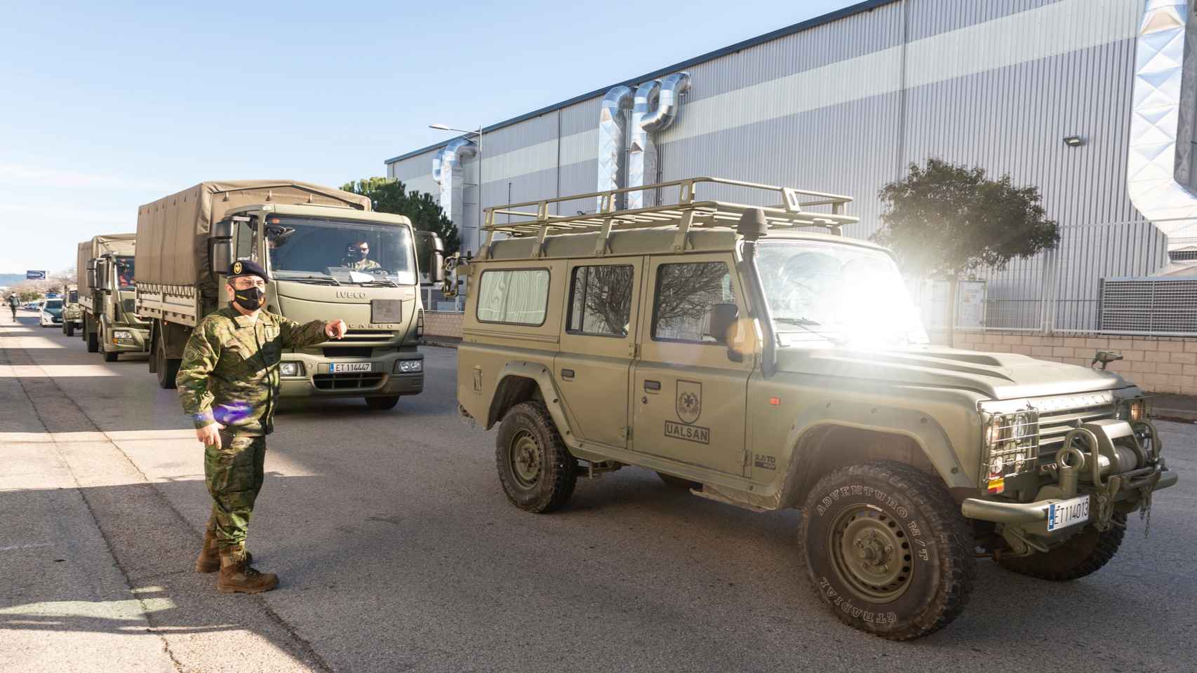 Vehículos militares salen del centro logístico de Pfizer.