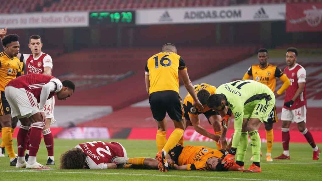 David Luiz y Raúl Jiménez, tumbados sobre el césped tras golpearse en la cabeza mutuamente durante un Arsenal - Wolverhampton