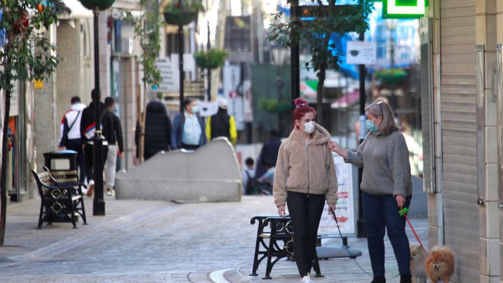 Dos personas caminando por la calle con mascarilla.