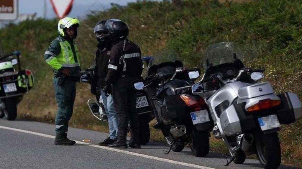 Un agente de la Guardia Civil dialoga con dos motoristas.