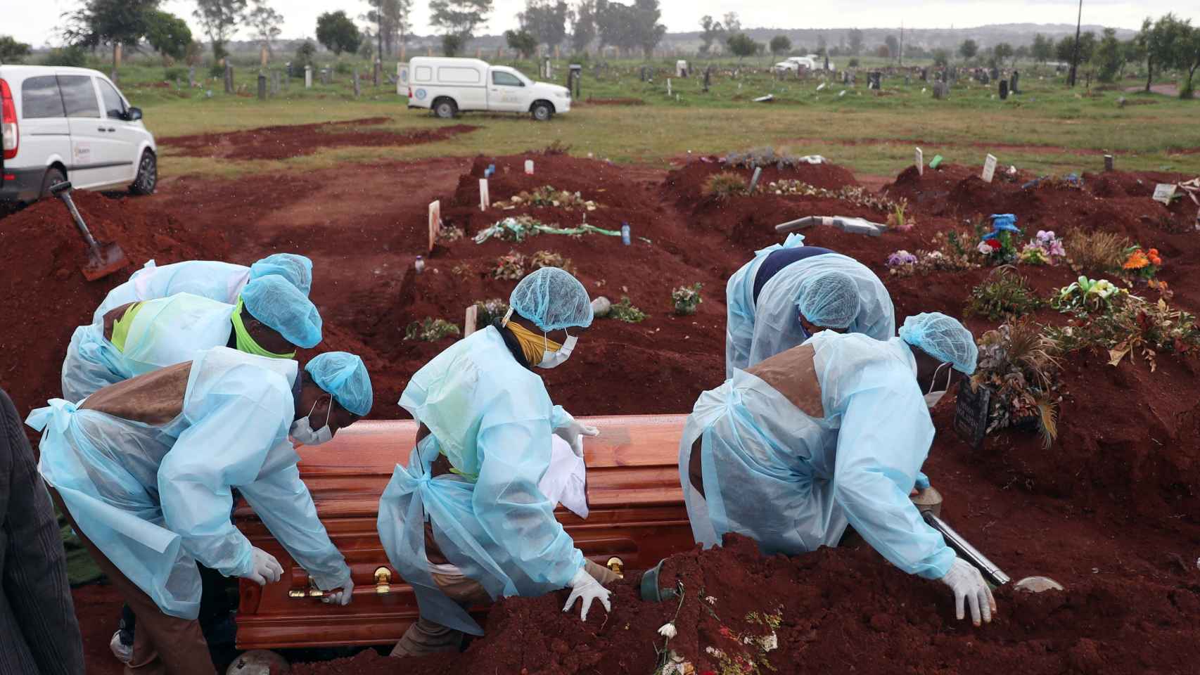 Trabajadores funerarios con EPIs entierran a una víctima fallecida por coronavirus en Joburg, Sudáfrica.