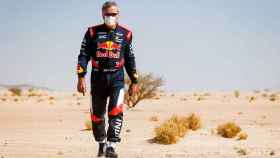Carlos Sainz camina por la arena del desierto en el Dakar 2021
