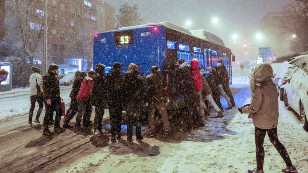 Varias personas empujan un autobús bajo una intensa nevada en la avenida Ramón y Cajal, en Madrid.
