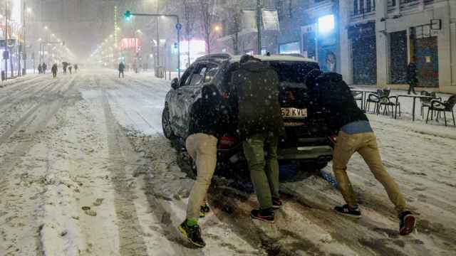 Imagen de unas personas en Madrid empujando un coche que ha perdido la tracción.
