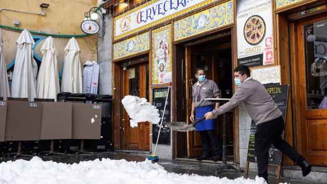 Un hombre retira nieve de la entrada de un establecimiento.