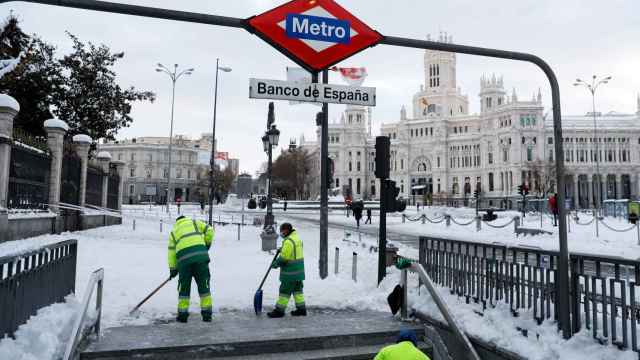 Unos operarios del Ayuntamiento de Madrid limpian la entrada a la parada de Metro de Banco de España.