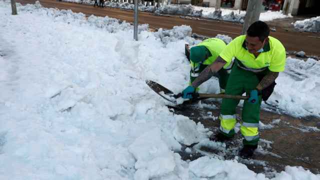 Unos operarios del Ayuntamiento de Madrid limpian la nieve acumulada en la plaza de Colón.