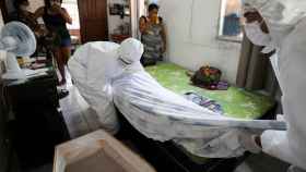 Trabajadores de una funeraria de Manaos retiran el cuerpo de una persona fallecida en su casa por coronavirus.