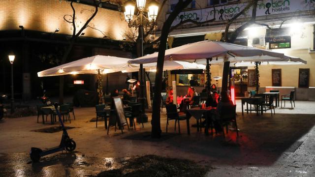 Un grupo de personas sentadas en una terraza en una plaza de Madrid.