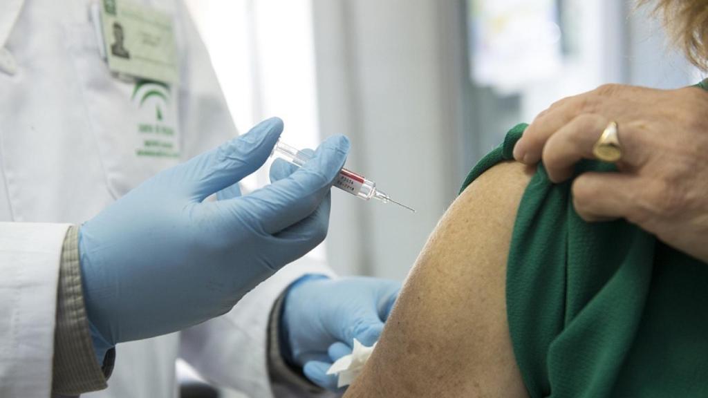 Un sanitario vacunando a una persona mayor.