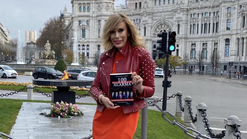 María Eizaguirre posa junto a su nuevo libro frente a la llama por las víctimas de la Covid en Madrid.