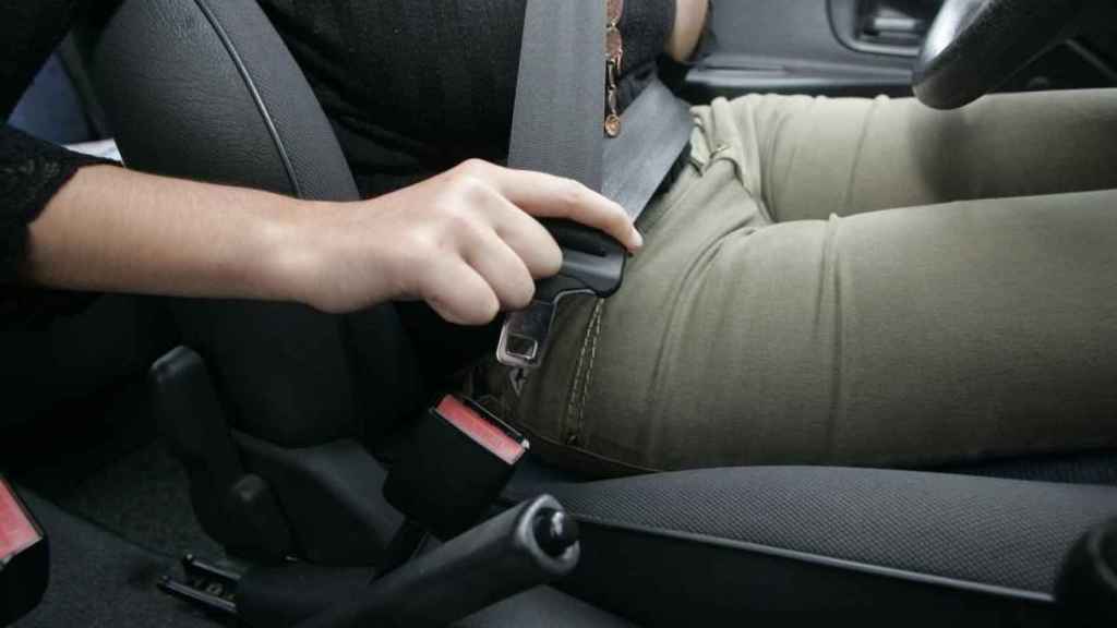Una conductora se abrocha el cinturón de seguridad en su vehículo.