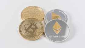 Monedas físicas con los símbolos del bitcoin y el ethereum.