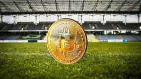 Una moneda de bitcoin en un campo de fútbol.