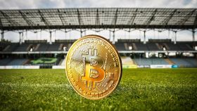 Una moneda de bitcoin en un campo de fútbol.