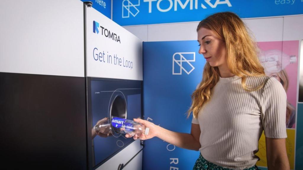 Una mujer deposita una botella en una máquina de Tomra, la multinacional noruega que financia un lobby ecologista en España.
