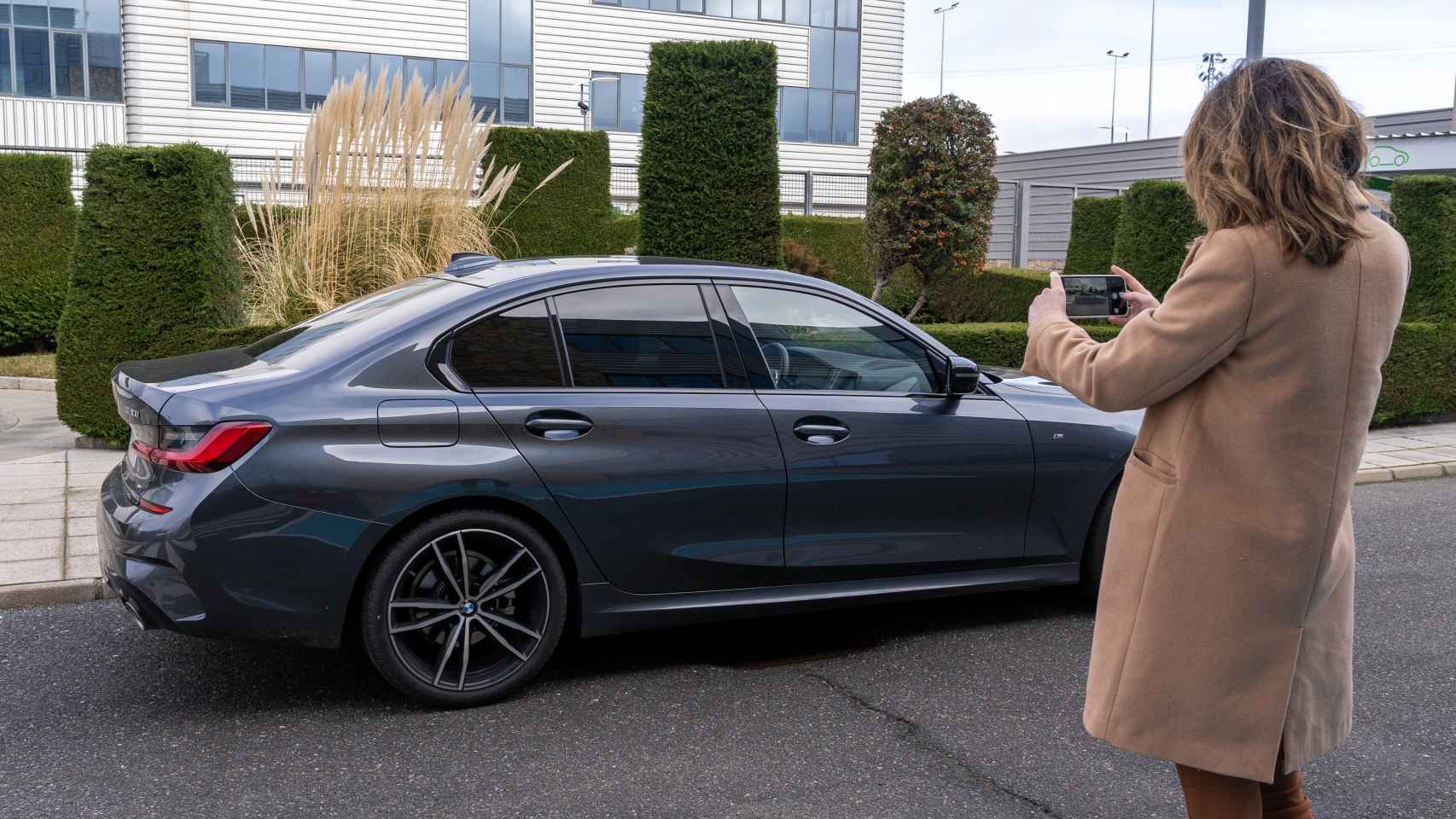 Una mujer toma fotos de un coche con su teléfono móvil.