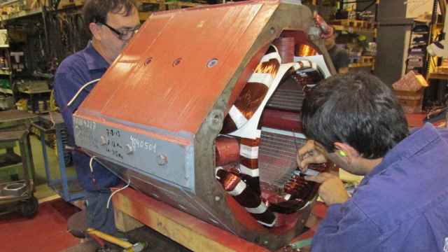 Dos técnicos de Motorlan reparando una pieza de un motor eléctrico industrial en su planta.