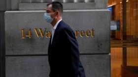 FILE PHOTO: A man wearing a protective face mask walks by 14 Wall Street, as the global outbreak of the coronavirus disease (COVID-19) continues, in the financial district of New York