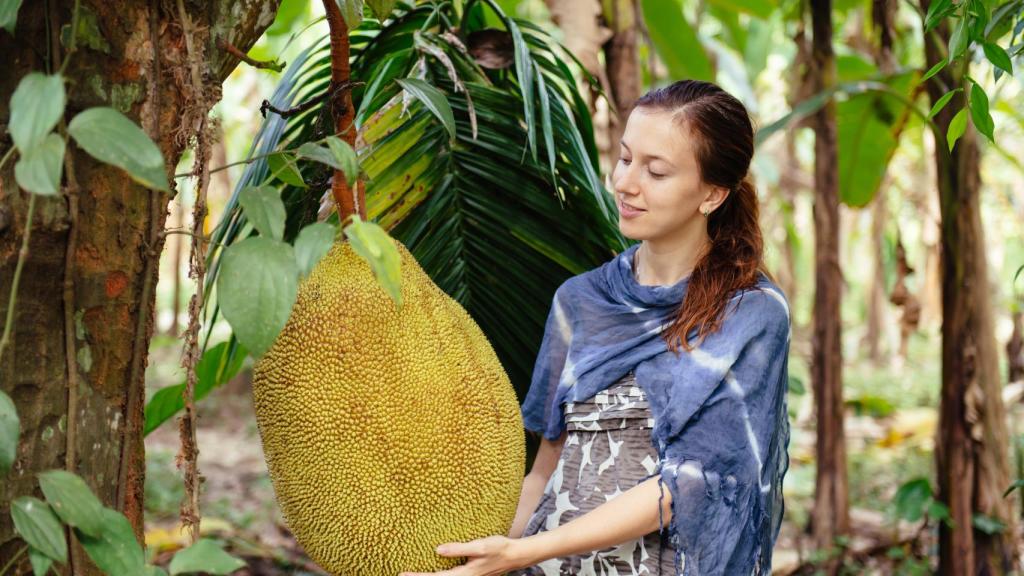 Una mujer junto a un ejemplar de jackfruit muy grande.