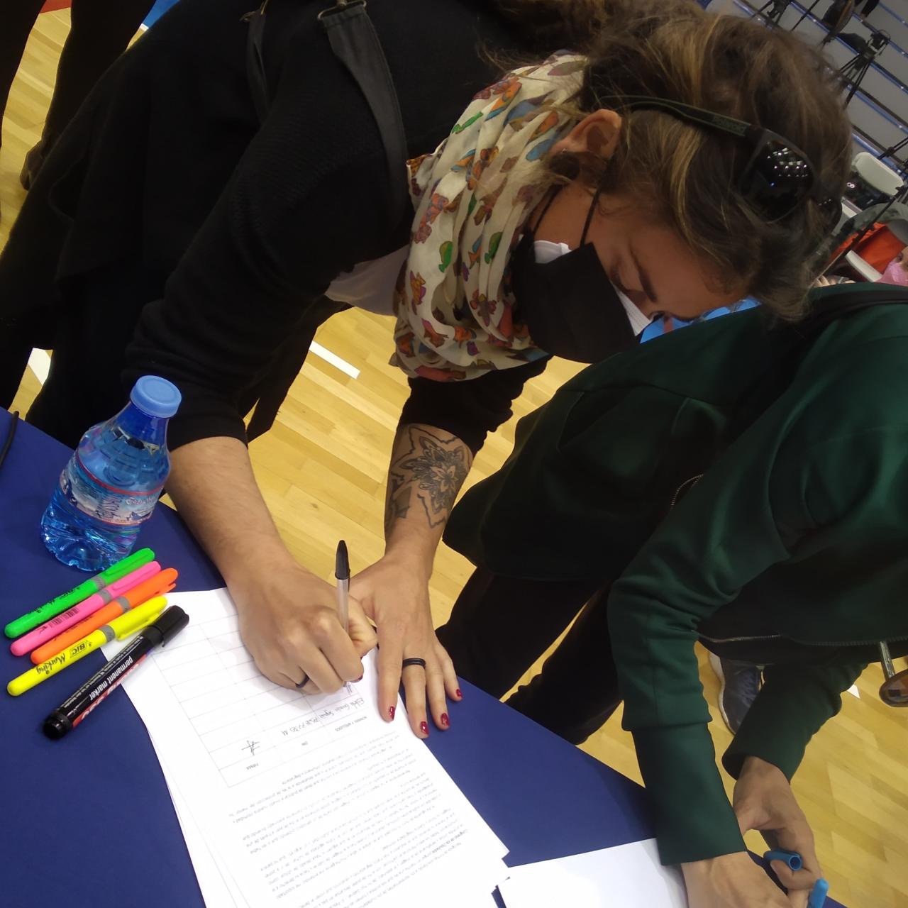 Dos amigas de Patricia estampando su firma en la campaña.