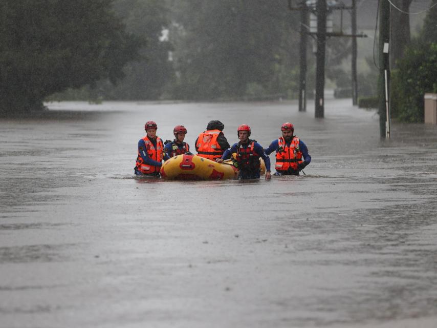 Un grupo de personas usa un bote hinchable para desplazarse a sus hogares.